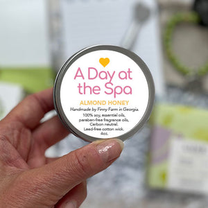 A DAY AT THE SPA CANDLE - A sweet almond and honey to soothe the room. 100% soy. Non-toxic. Carbon-neutral. Lead-free cotton wick. Made with essential oils and paraben-free fragrance oils. Hand-poured into a travel tin with lid. Handmade by Finny Farm in Georgia. 4oz.