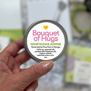 BOUQUET OF HUGS CANDLE&nbsp;- 100% soy. Non-toxic. Carbon-neutral. Lead-free cotton wick. Made with essential oils and paraben-free fragrance oils for a sweet bouquet of honeysuckle and jasmine. Hand-poured into a travel tin with lid. Handmade by Finny Farm in Georgia.