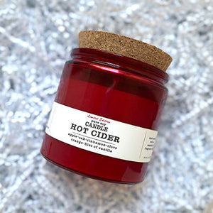 HOT CIDER SOY CANDLE - The warm scent of oak barrel apple cider combined with mulled spices of clove, cinnamon, hints of orange and vanilla. 100% soy candle. Handmade by Turnrow Bath, Body &amp; Home in Georgia. Comes in red glass vessel with cork lid that can be reused as a planter or holder for treasures. 10 oz. 30 hr + burn time. Photo creidt: Turnrow Bath, Body & Home